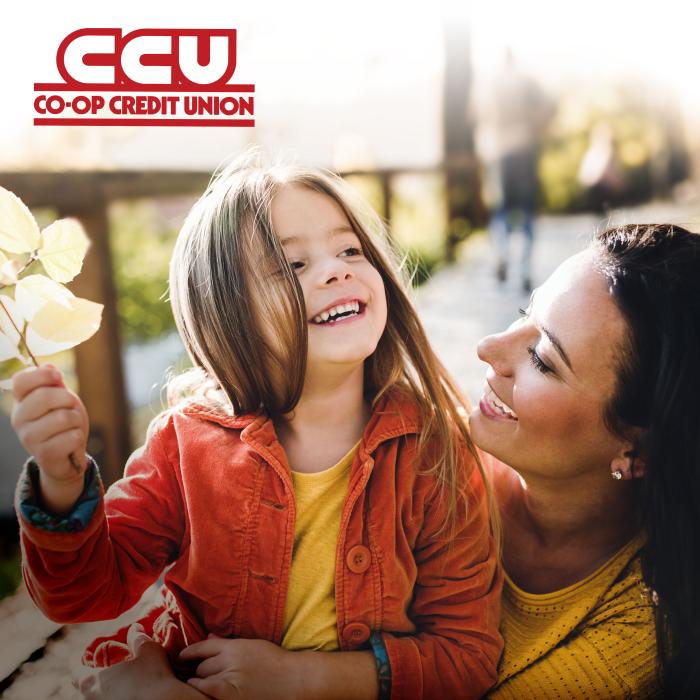 Co-op Credit Union logo atop an outdoor photo of a smiling woman holding a smiling young girl who is holding a leafy branch