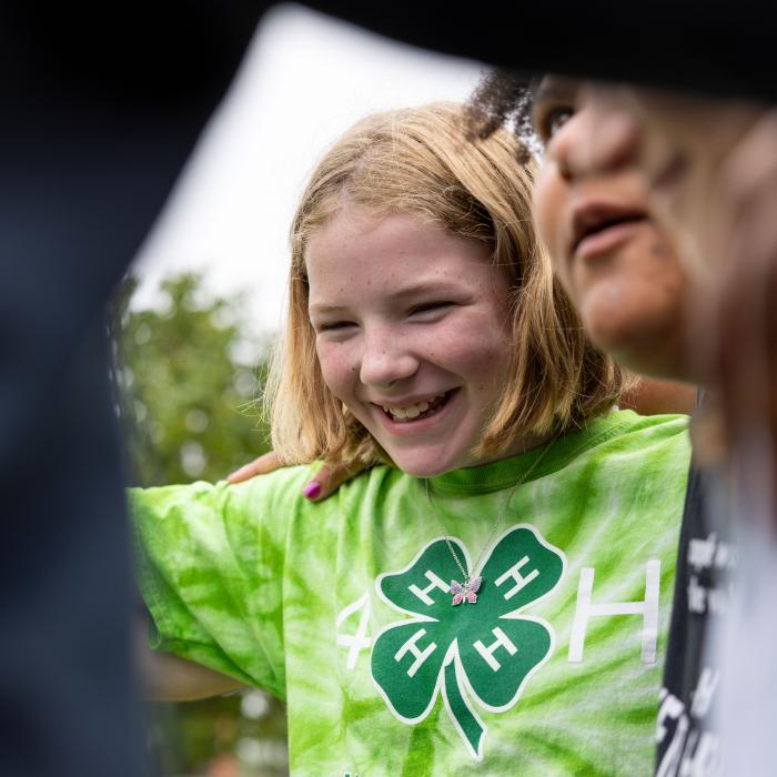 Happy young girl wearing a green four leaf clover 4-H shirt.