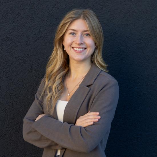 Woman smiling against a dark grey background.